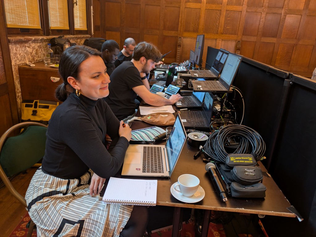 Photograph of a person sat at a desk with their laptop and notepad.