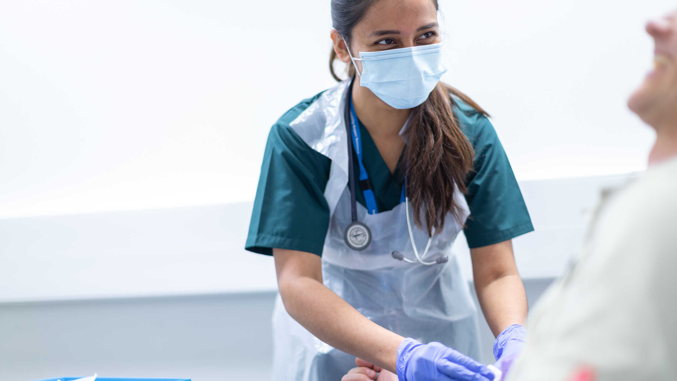 Photograph of a medical staff member interacting with a human challenge study participant.