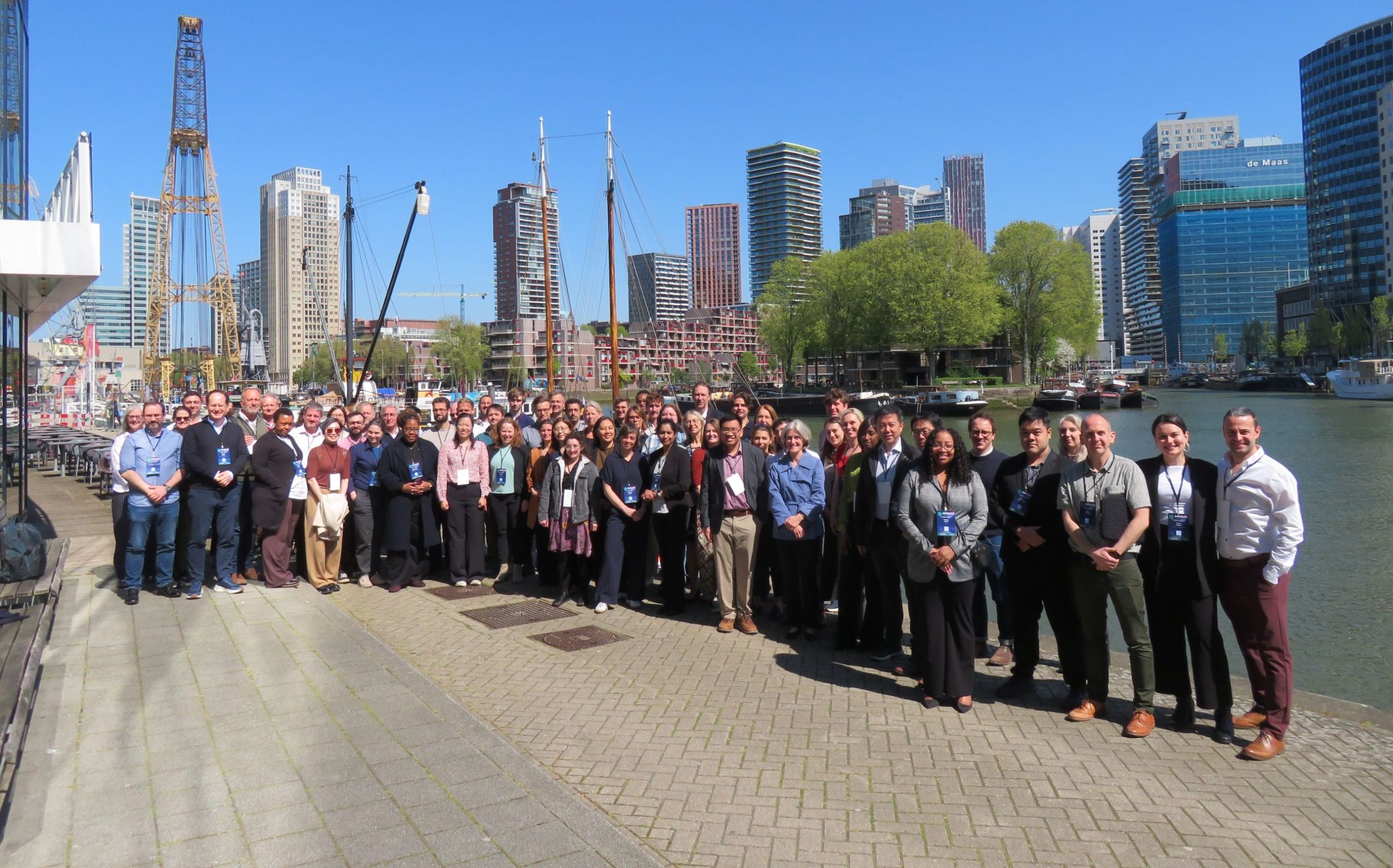 Photograph of the MUSICC consortium members stood on a dockside in front of the Rotterdam skyline on a sunny day at the 2026 Annual Meeting.