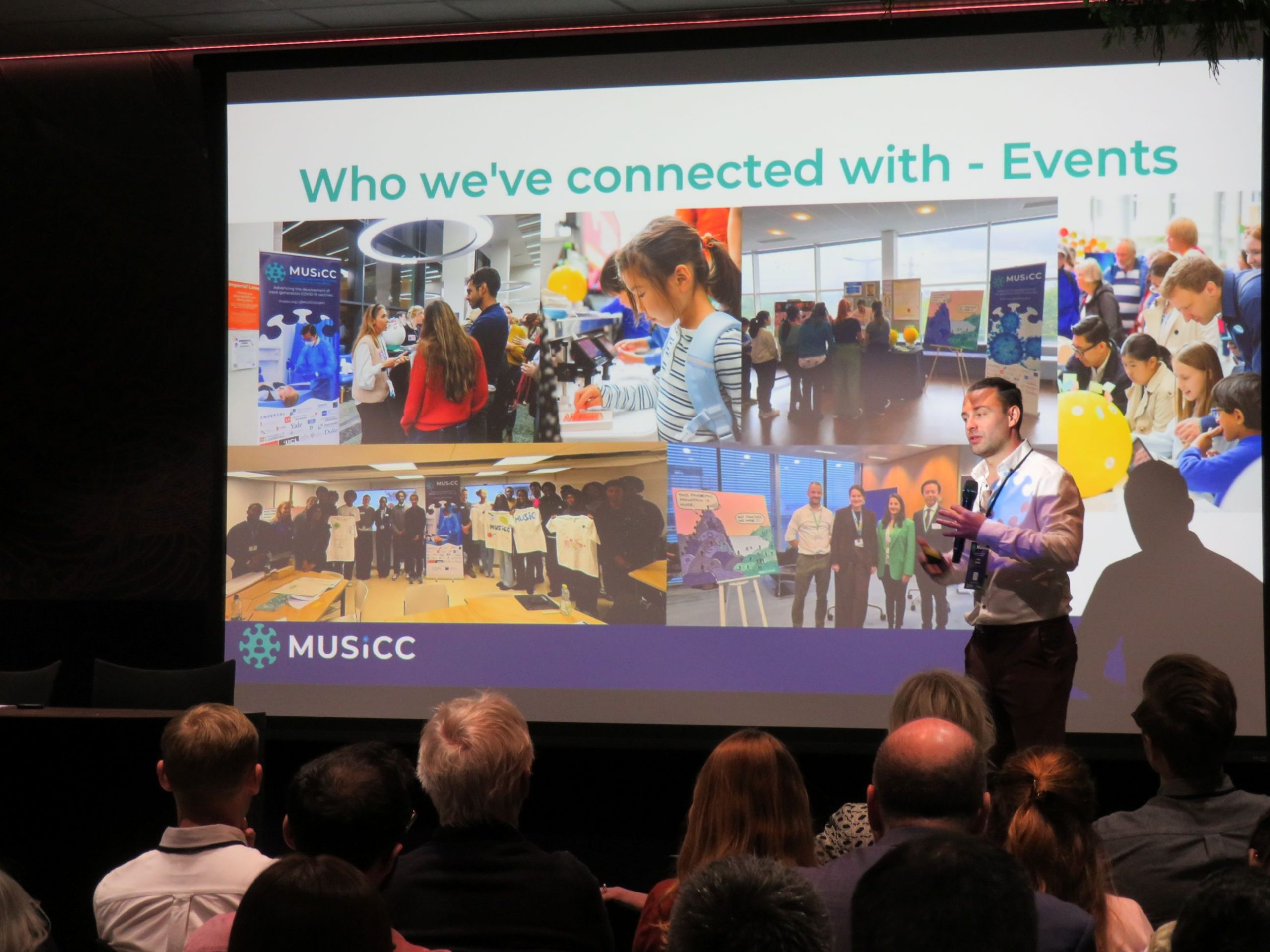 Photograph of Mike Darkes presenting on stage in front of a screen, at the 2026 Annual Meeting, showing photos from MUSICC's various engagement events.