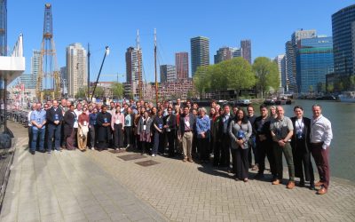 Photograph of the MUSICC consortium members stood on a dockside in front of the Rotterdam skyline on a sunny day.