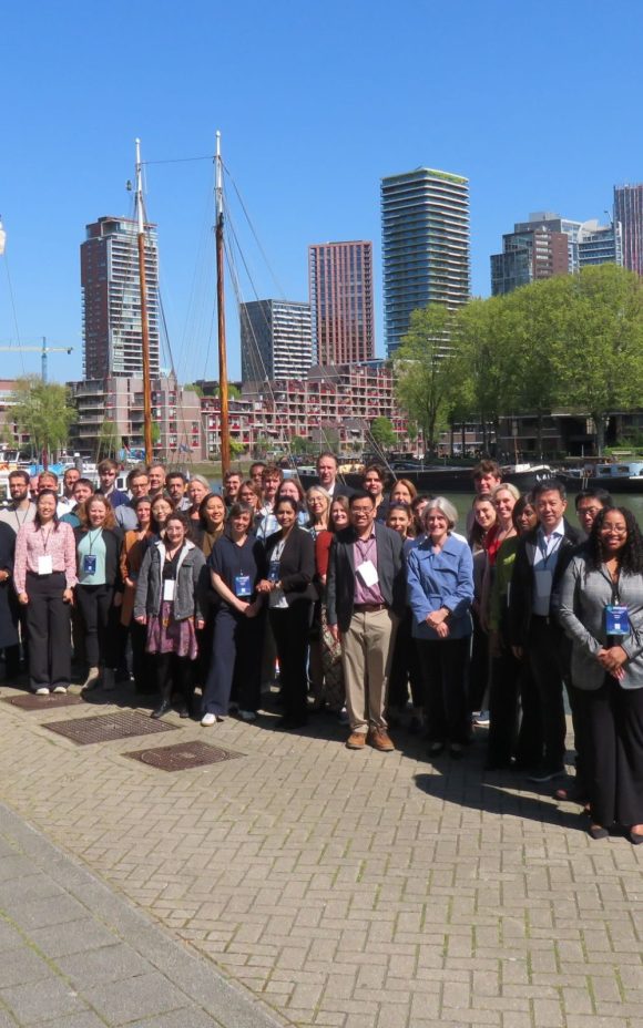 Photograph of the MUSICC consortium members stood on a dockside in front of the Rotterdam skyline on a sunny day.